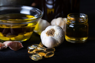 Cold pressed garlic oil in bowl with  garlic oil capsule on dark background. Garlic Improves...