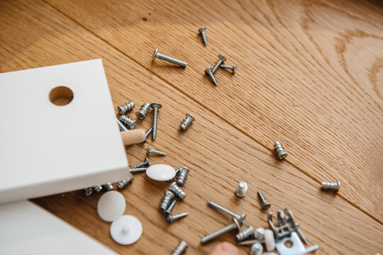 View from above of multiple screws and bolts during white furniture assembly in the new home - attention to details