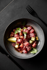 The vertical frame. Fresh red tuna, avocado, sesame and lime salad on a black background