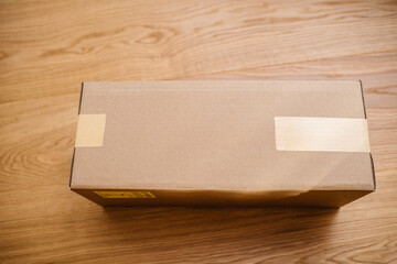 Overhead view of parcel cardboard box on the wooden parquet floor secured with scotch tape from both sides