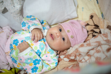 Three month old baby girl laying in a warm bed during the winter cold