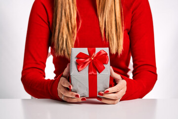 Closed plan of a woman with a red sweater and a gift box in her hands isolated on a white background.