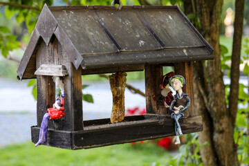 Naklejka premium A colorful ceramic doll waiting for the birds in feeder for the birds