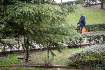 Close up photo of a tree branch at the beginning of a snowfall while we see in the background a man...
