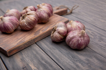Garlic bulbs and a cutting board on a wooden table. Rustic style.