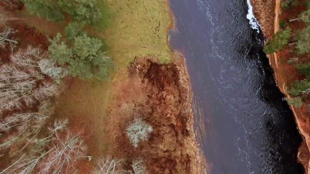 Red sandstone cliffs in the banks of river Salaca during late autumn time, Latvia. Real time drone footage