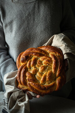 Woman holding homemade braided yeast bread in towel .