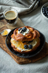 Breakfast with homemade brioche bun with cream cheese, orange jam and blueberries and espresso coffee.