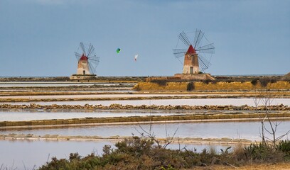 Windmühlen in den Meerwassersalinen von Trapani auf Sizilien. Die Salzgewinnung beruht auf den...