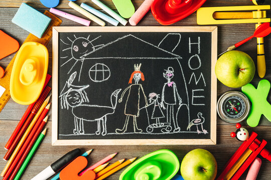 Children's drawing of a family on a chalk board among scattered toys