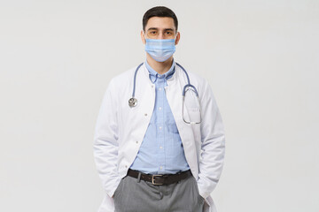 Young doctor wearing surgical mask is ready to help patients with coronavirus or covid virus, isolated on gray background