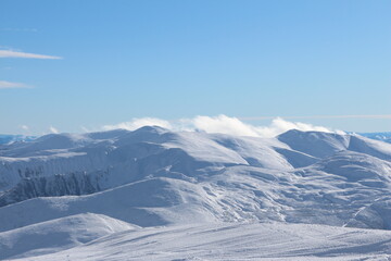 White clouds above the snow covered mountains