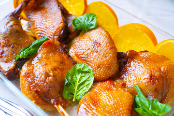 Tasty roast duck made in orange sauce. Oven-baked duck garnished with oranges and spinach. Close-up view.