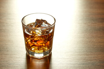 A Glass of whiskey on ice on wood table