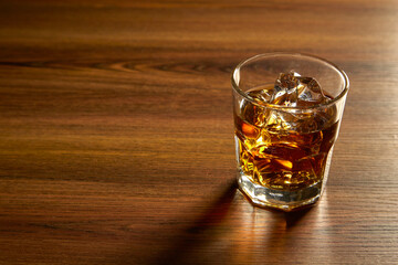 A Glass of whiskey on ice on wood table