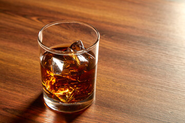 A Glass of whiskey on ice on wood table