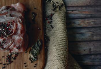 A piece of fresh eco meat with pepper on the wooden cutting board and burlap 