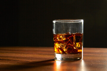 A Glass of whiskey on ice on wood table