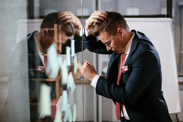 Businessman in conference room use sticky notes on glass wall. Handsome businessman making a business plan..