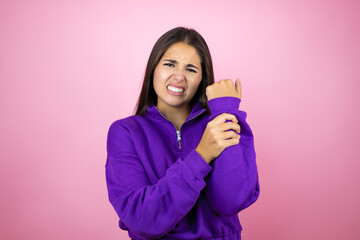 Young beautiful woman wearing sweatshirt over isolated pink background suffering pain on hands and fingers, arthritis inflammation