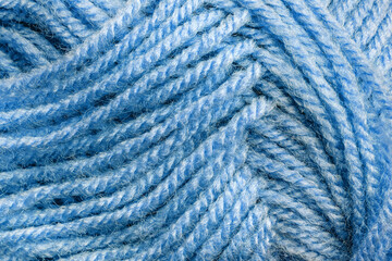 Cropped skein of pale blue woolen knitting thread texture. Ball of soft woolen yarn full frame macro photography. Knitting threads for handicraft and home hobbies background. Close-up design element.