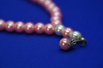 Selective focus on pink bead tasbih or tasbeeh isolated on blue background.
