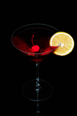 Cocktail with cherries and a lemon wedge on a mirror surface.
