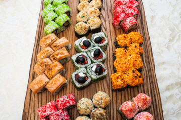 Different types of delicious and juicy sushi and rolls on a wooden board