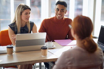 satisfied afro-american male looking with smile at candidate for job while his caucasian female...