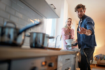 A young couple is posing for a photo while doing housework. Kitchen, housework, home, relationship