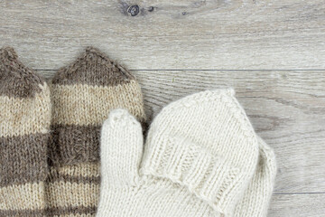 Fototapeta na wymiar Knitted mittens on a wooden background. Mittens with a flap. The concept of hobby, home production and individual entrepreneurship.