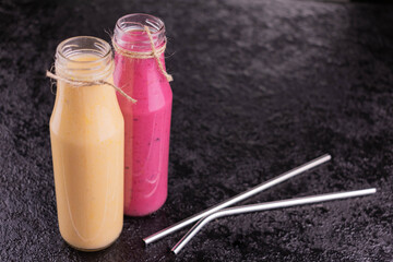 Two smoothies in bottles on a black background.Copy space.