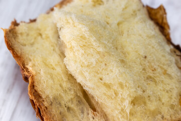 Closeup Broken Panettone Bread on white table. Panettone (panetton) is an Italian type of sweet bread originally from Milan and usually prepared for Christmas and New Year