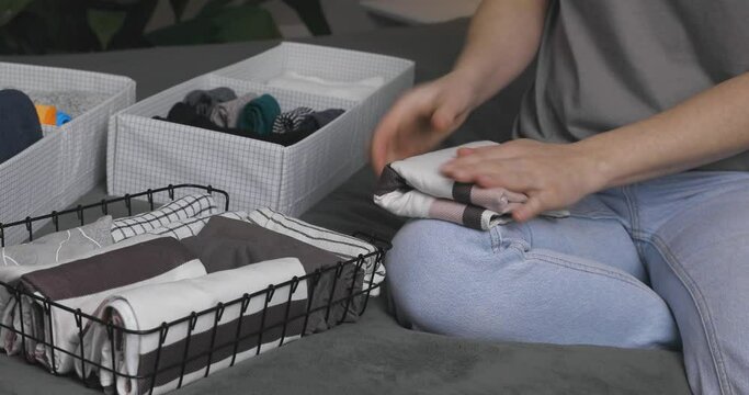 Vertical storage of clothing.Women organize clothes in a modern bedroom. Women sorting clothes in baskets room cleaning concept.