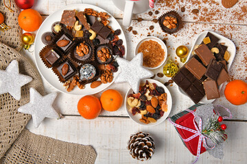 sweet food top view background for merry christmas or new year holiday decoration - chocolate candies, tangerines, cookies on white wood
