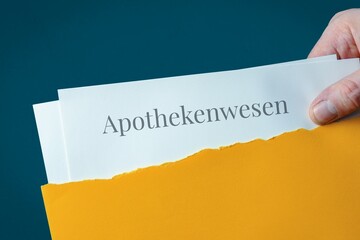 Apothekenwesen. Briefumschlag wird geöffnet. Hand entnimmt Unterlagen. Text auf Post-Brief.