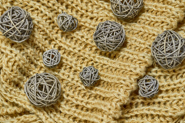 Large and small balls of rattan on knitted fabric. Golden background. View from above