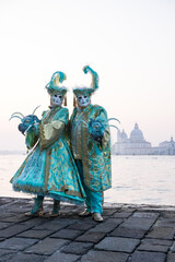 Fototapeta na wymiar Venice, Italy - February 18, 2020: An unidentified couple in a carnival costume in front of Santa Maria della Salute, attends at the Carnival of Venice.