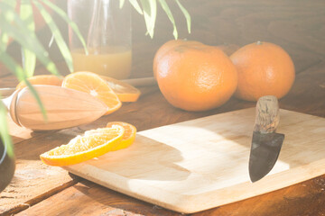 sliced oranges on a chopping board on a wooden table in the kitchen. Squeezing juice from oranges