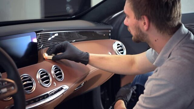 Cleaning car interior and spraying with cleaning disinfection liquid on the leather dashboard of the vehicle.