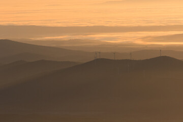 Winter in the Mountains. Beautiful orange mist or fog at sunrise time. Good sunlight and patterns in the landscape. Sea of clouds.