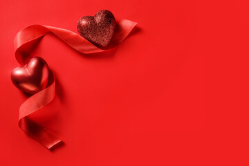 Two hearts and a red ribbon on a red background with copy space.