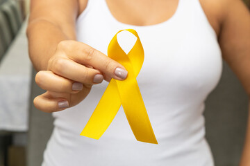 Young woman, with pink t-shirt, holding yellow ribbon, preventing aids.