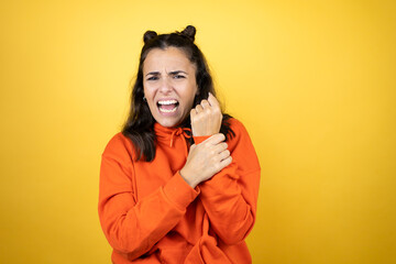 Young beautiful woman wearing sweatshirt over isolated yellow background suffering pain on hands...