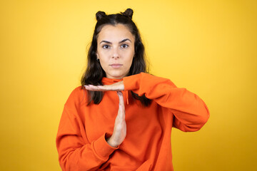 Young beautiful woman wearing sweatshirt over isolated yellow background Doing time out gesture...