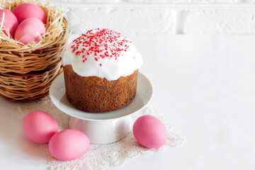 Easter composition with wicker basket with pink colored eggs and decorated Easter cake
