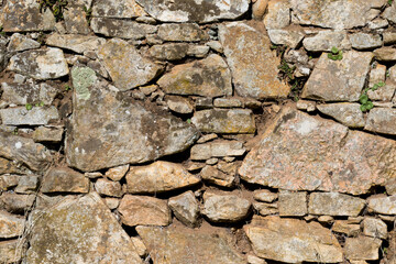 Old stone rock wall surface texture with grass. Close up detail. Pattern abstract background.
