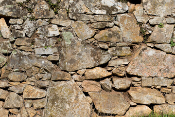 Old stone rock wall surface texture with grass. Close up detail. Pattern abstract background.