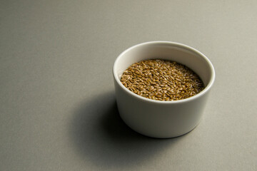 flax seeds in a white round bowl on a gray background
