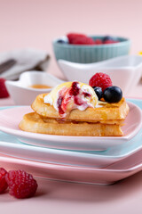 Heart shaped  belgian waffles with Ice-cream and berries on pink background. Tasty breakfast. Close-up.